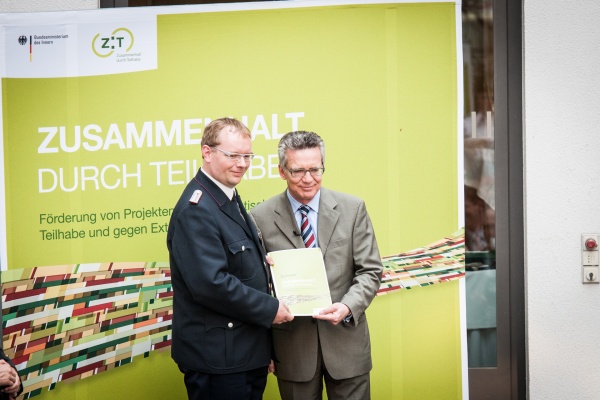 Der Bundesminister des Innern, Dr. Thomas de Maizière übergibt das Demokratieberater-Zertifikat an Dirk Bönning aus dem Landesfeuerwehrverband Mecklenburg-Vorpommern e.V.