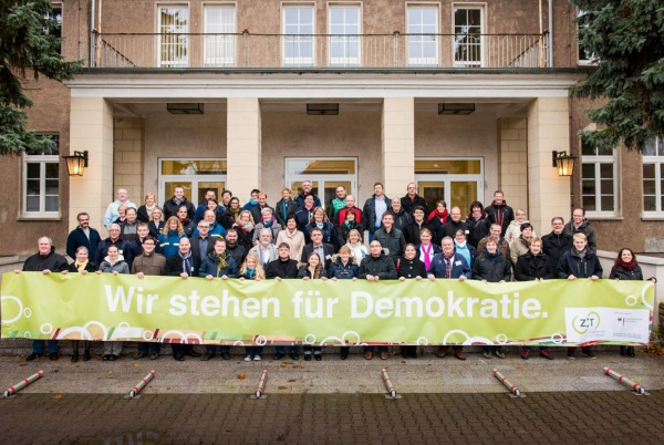 70 Demokratietrainer halten ein Banner mit der Aufschrift: "Wir stehen für Demokratie"